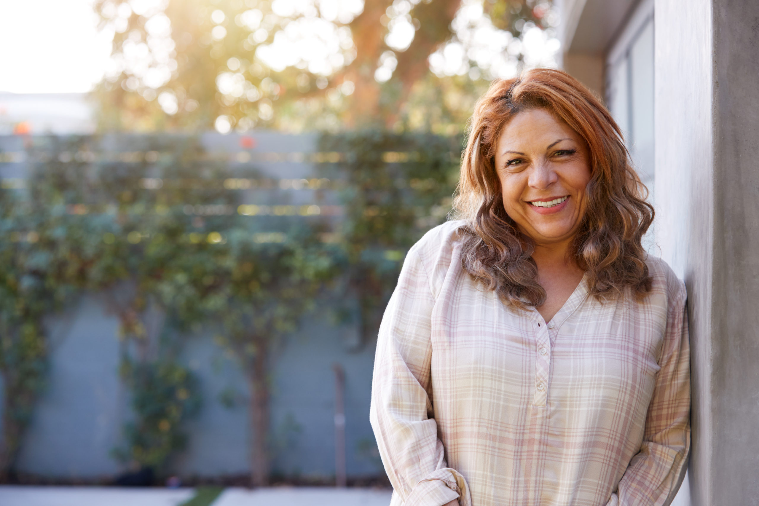 Photo of a smiling middle aged woman in a garden outside her home