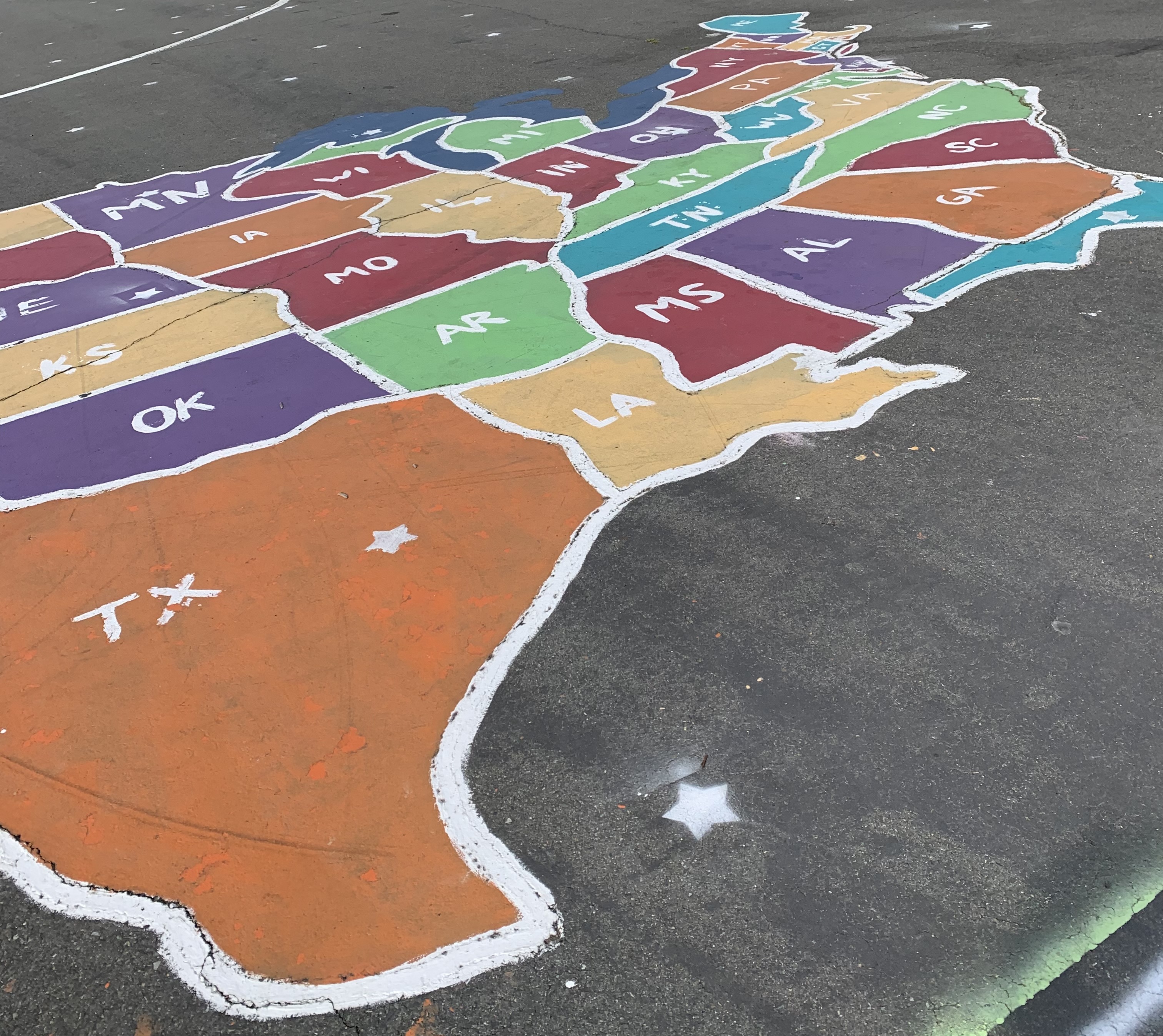 Photo of a painting on a playground of the United States with each state painted a different color.