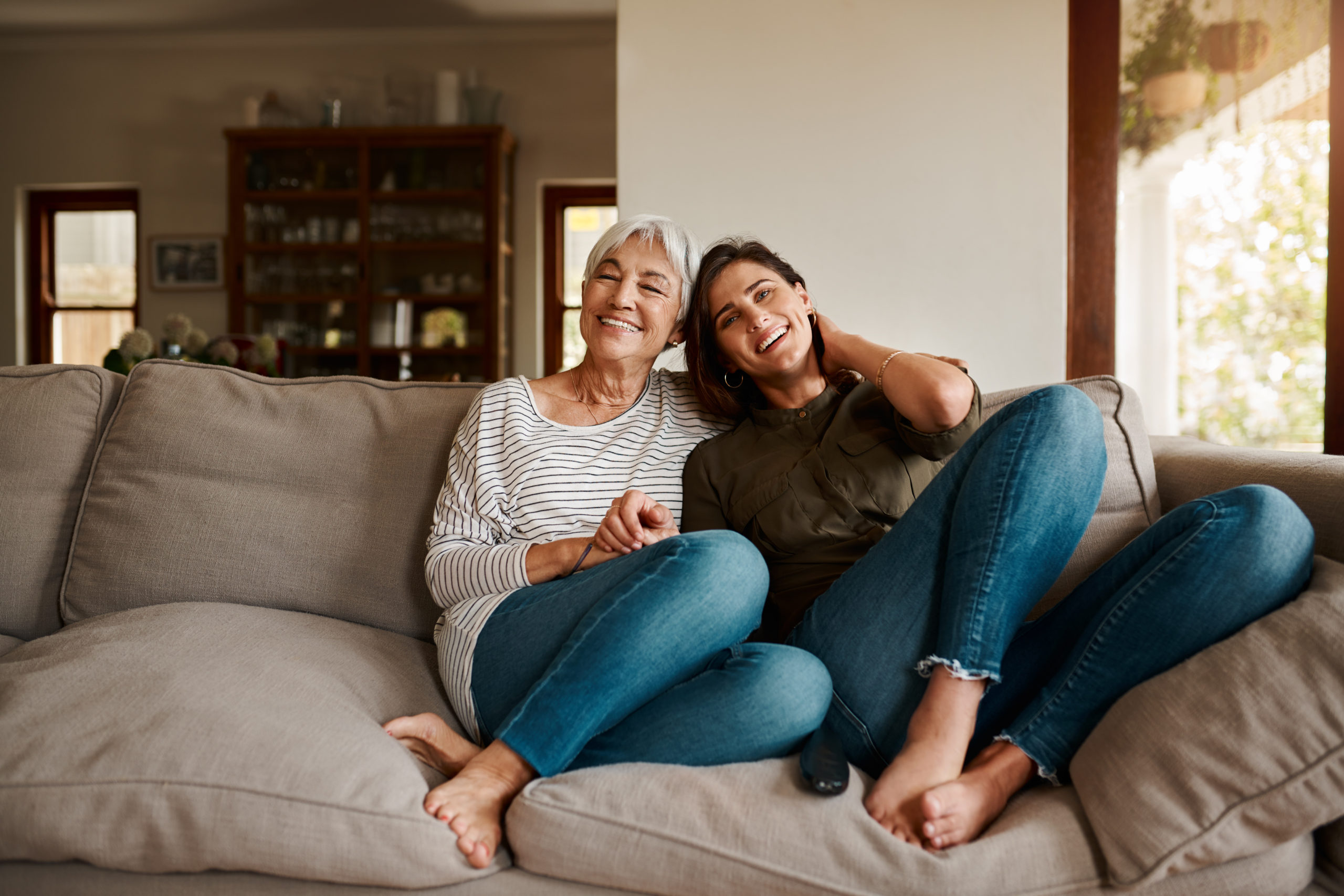 Full length portrait of an affectionate young woman spending time with her elderly mother in their living room at home.