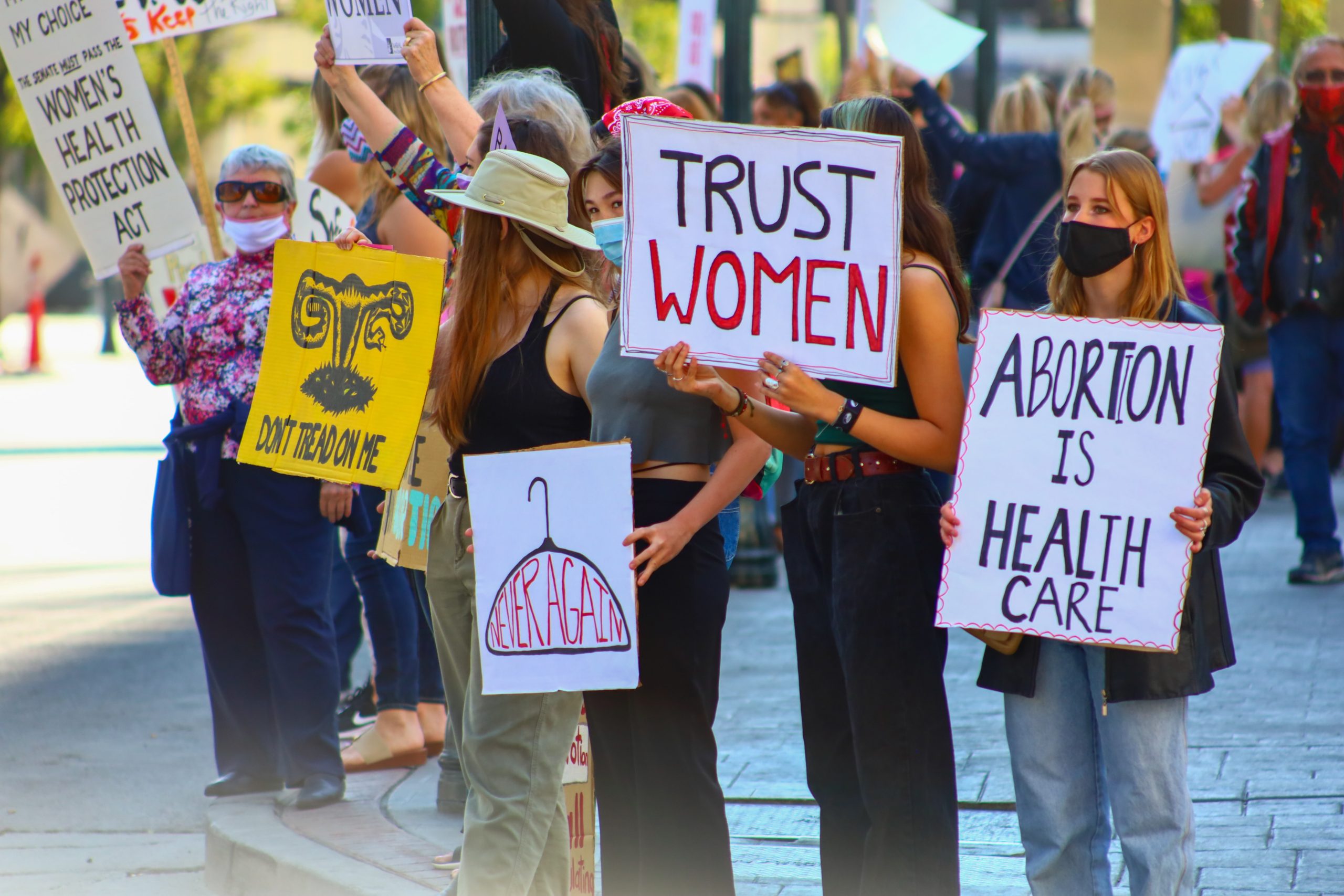 Photo of a small group of pro-choice protesters. Signs read "Abortion is Healthcare" and "Trust Women"