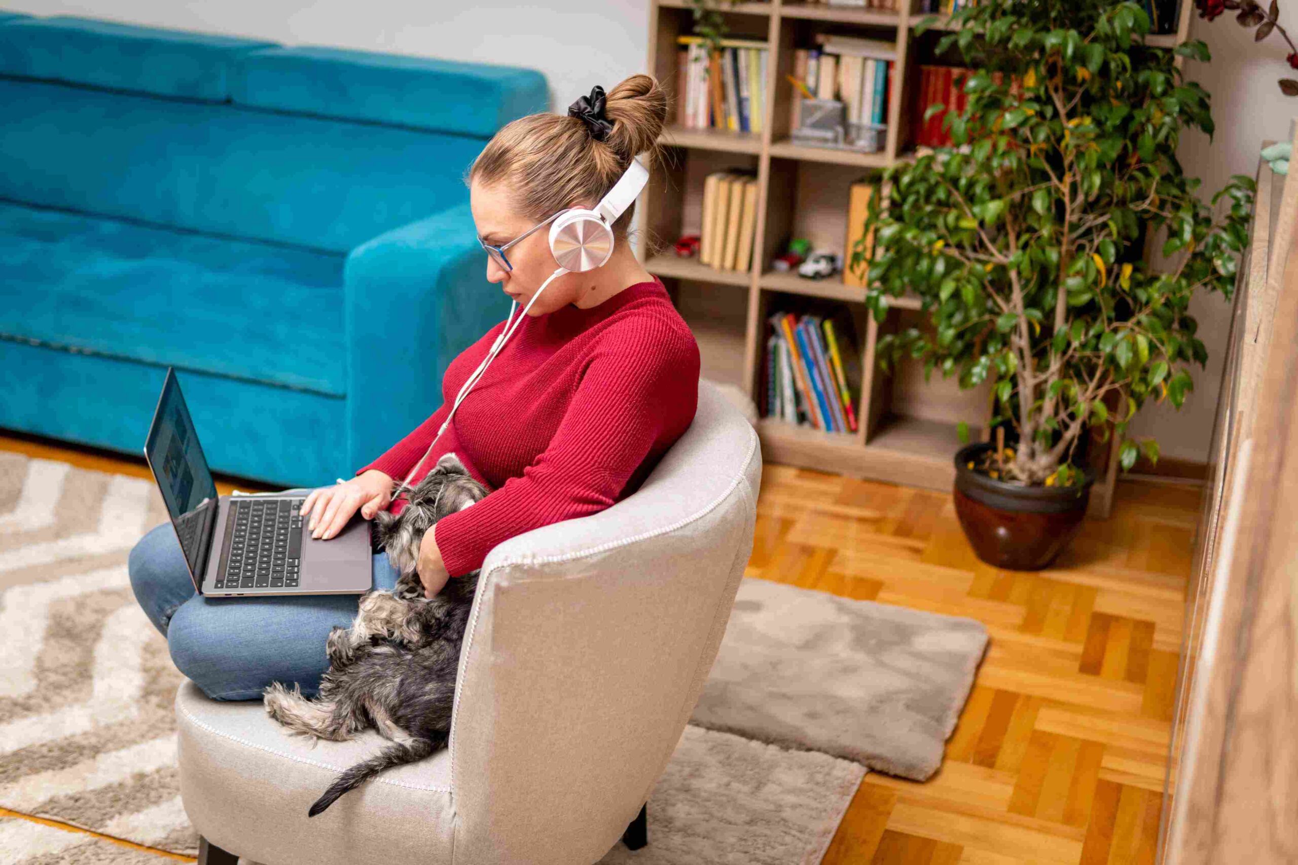 Photo of a young woman in headphones watching something on her laptop.