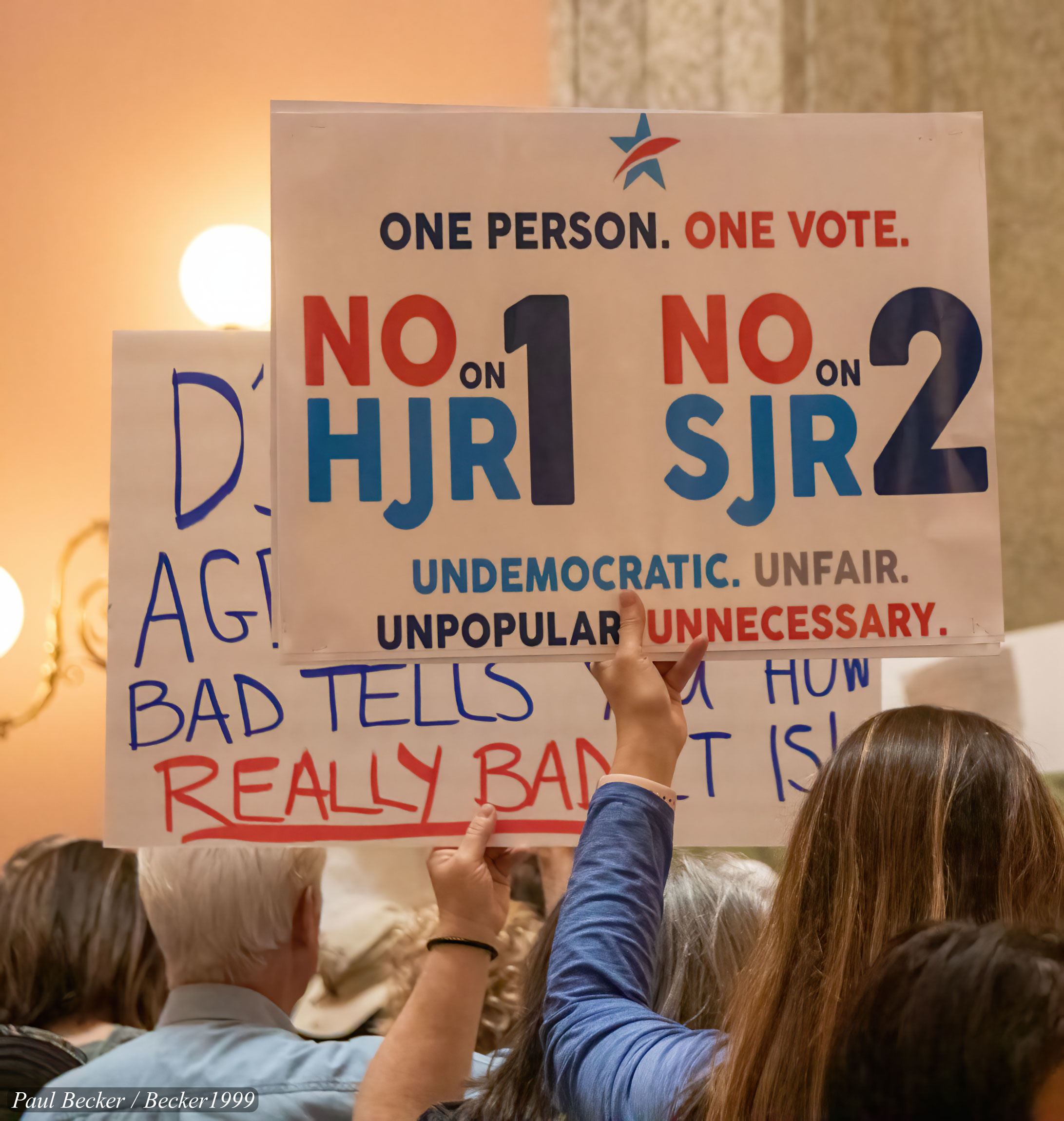 Photo of a group of Ohio voters holding signs including one that says "One person. One vote. No on HJR1, No on SJR2. Undemocratic. Unfair. Unpopular. Unnecessary.