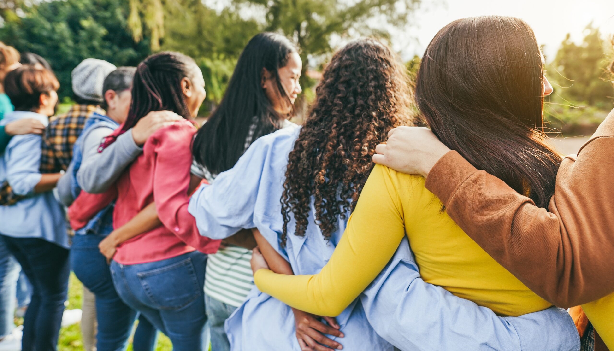 group of women with arms around each other shown from behind