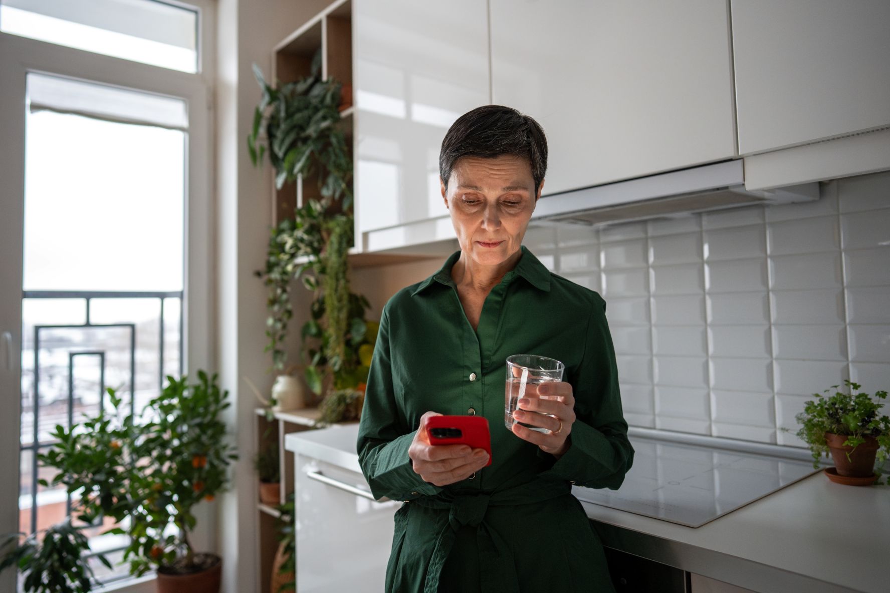 woman looking at smartphone in her kitchen