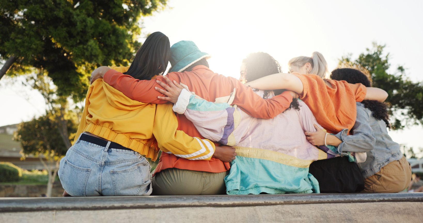Several women sitting with their arms around each other, as seen from behind